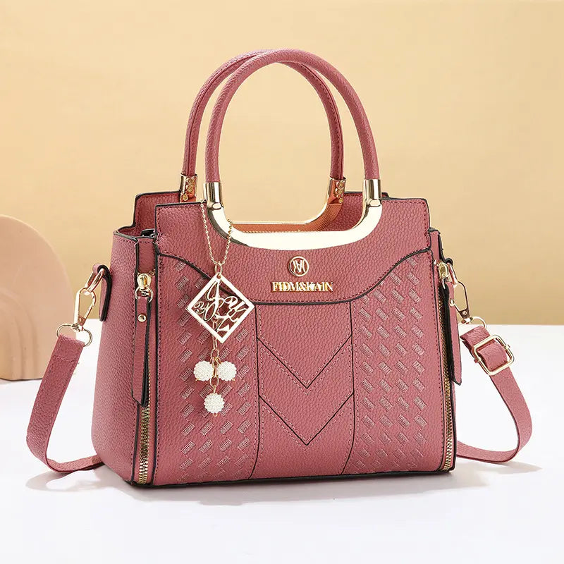 Dámska crossbody kabelka s prešívaním v tvare písmena V, kovaniami v zlatej farbe, viacerými priehradkami a hornou rukoväťou.
